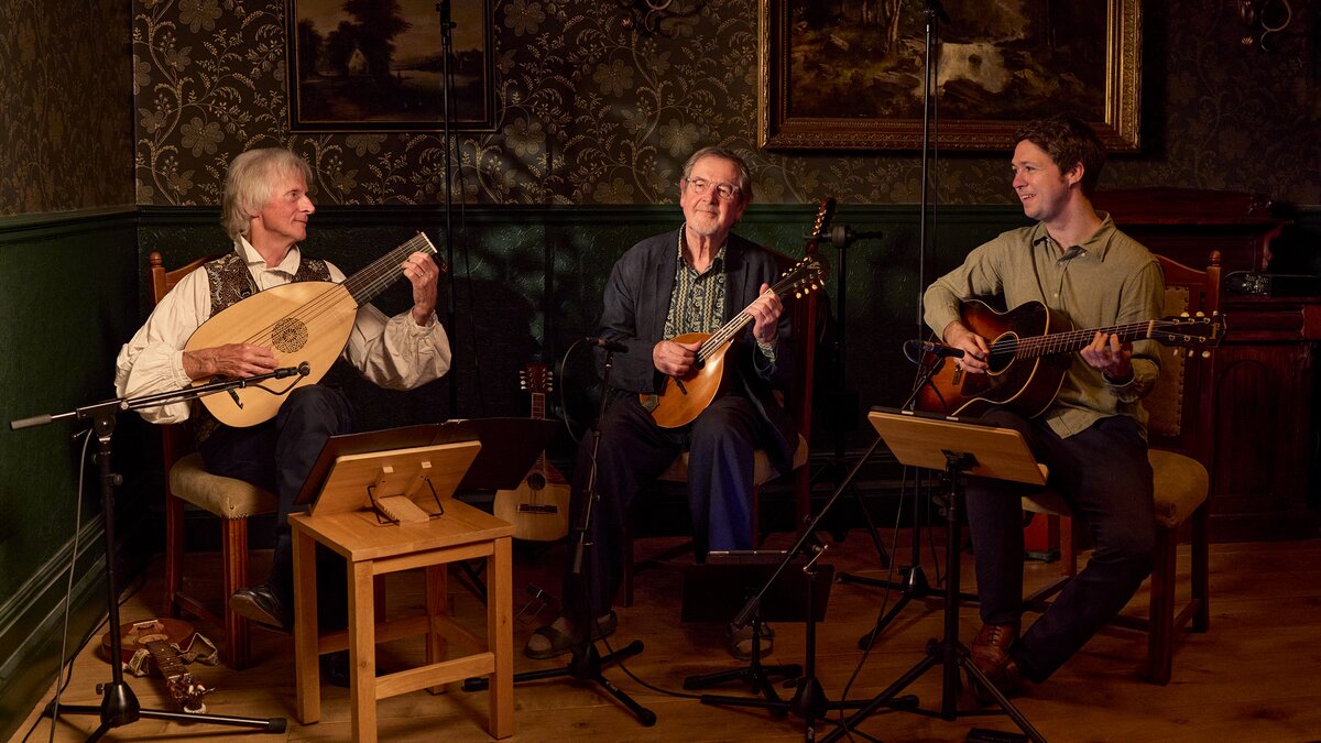A trio of men playing fretted string instruments.