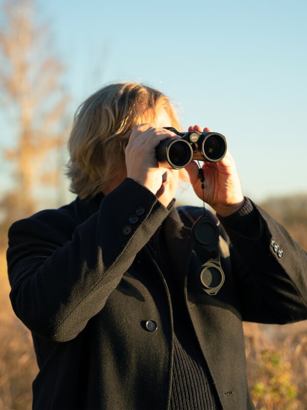 Dominik Eulberg with binoculars in a field. Photo by Larissa Matheus.