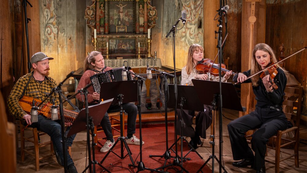A musical quartet performing nyckelharpa, accordion, viola, and violin