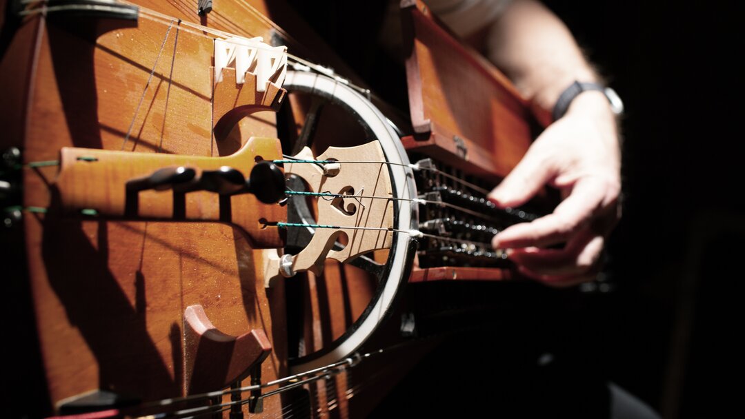 A close-up of hands on a hurdy-gurdy