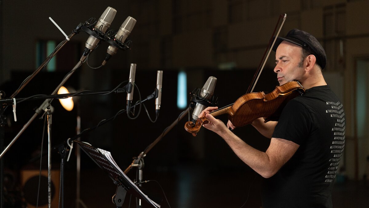 Aleksey Igudesman plays a violin in front of several microphones
