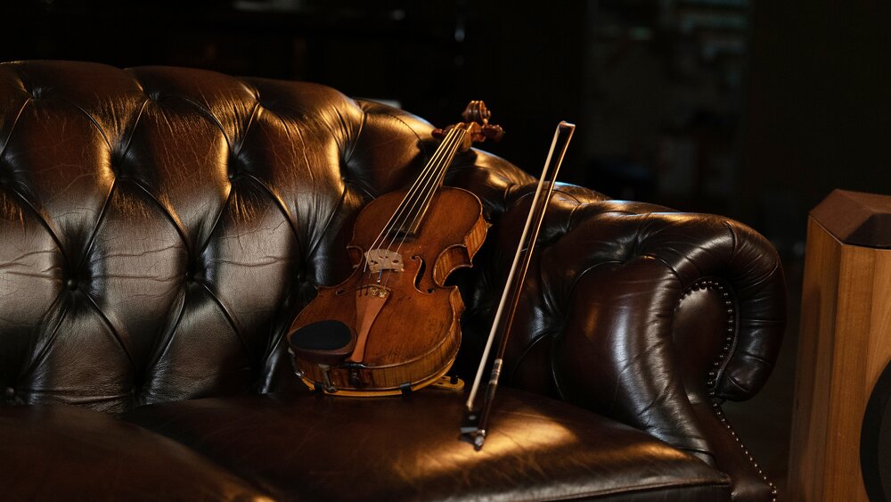 A very nice violin on a leather couch